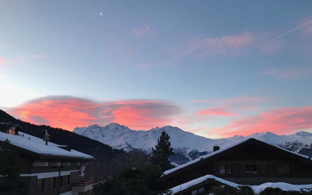 A sunset in the mountain with the view of the moon at the top